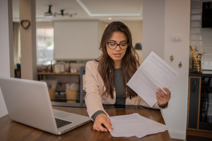 A woman reviewing business records and documents that she needs to file LLC taxes.